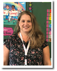 Jennifer Taylor, First Grade Teacher Jennifer Taylor - Woman with long brown hair wearing a black floral print dress