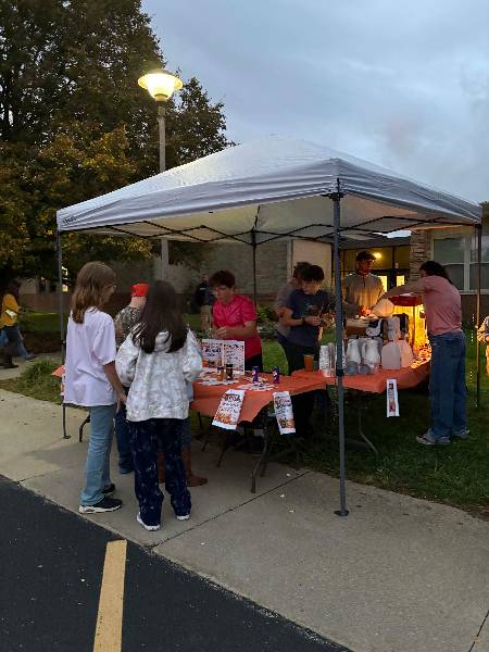 Students serving hot cider at dusk