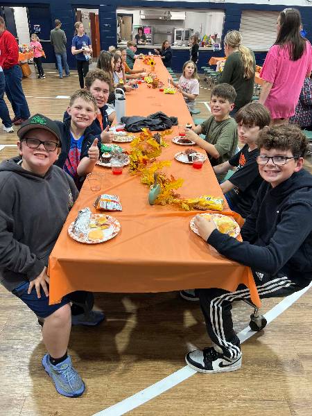Boys giving a thumbs up at dinner