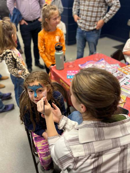 Student volunteer painting a girl's face