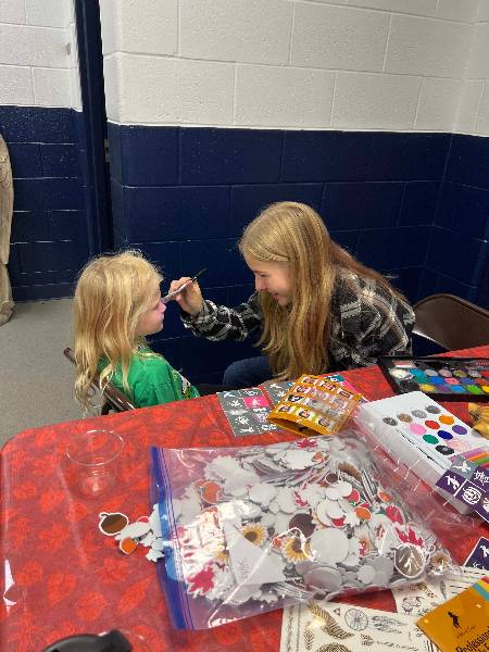 Volunteer painting a little girl's cheek