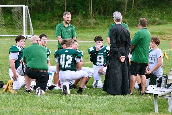 Coaches and Father talk with the football team before kickoff